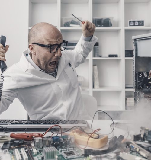 Burning computer on the technician desk, he is shocked and scared